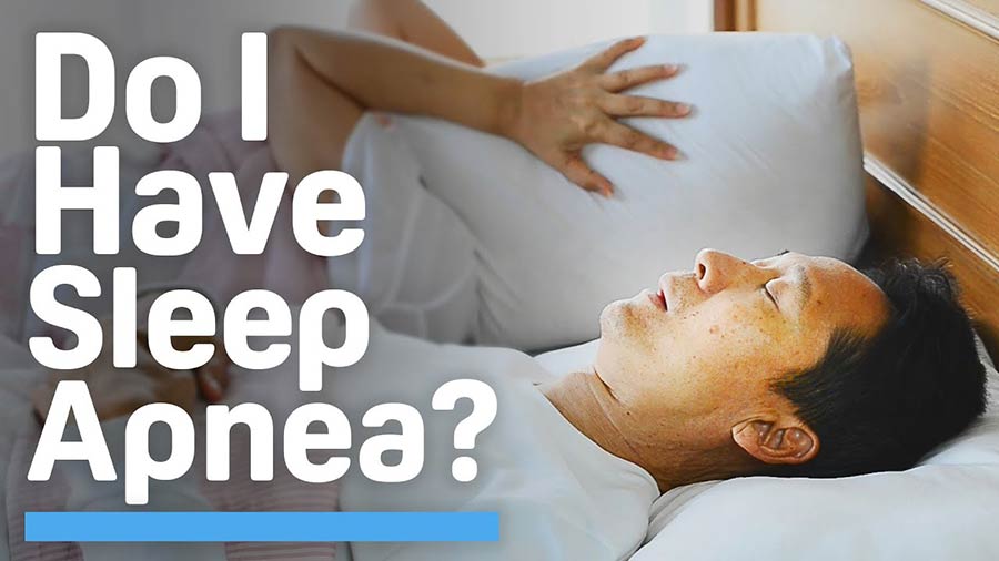 Video still of a man snoring while his wife covers her ears with a pillow with overlaying white type