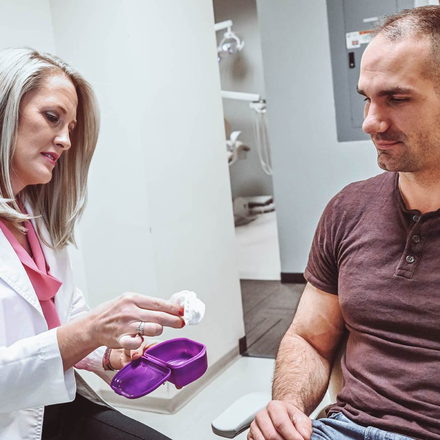 Photo of patient talking to dentist while receiving mouthpiece for sleep apnea